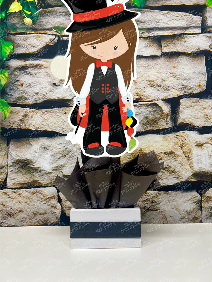 Kids birthday party magician themed centerpieces. The centerpieces feature illustrated cutouts including playing cards, a white rabbit in a tuxedo, a girl magician, a boy magician, a rabbit popping out of a top hat, and a magician's hat with a wand. Each cutout is set in a red, white, or black base filled with matching tissue paper. Receive fully assembled like pictured.