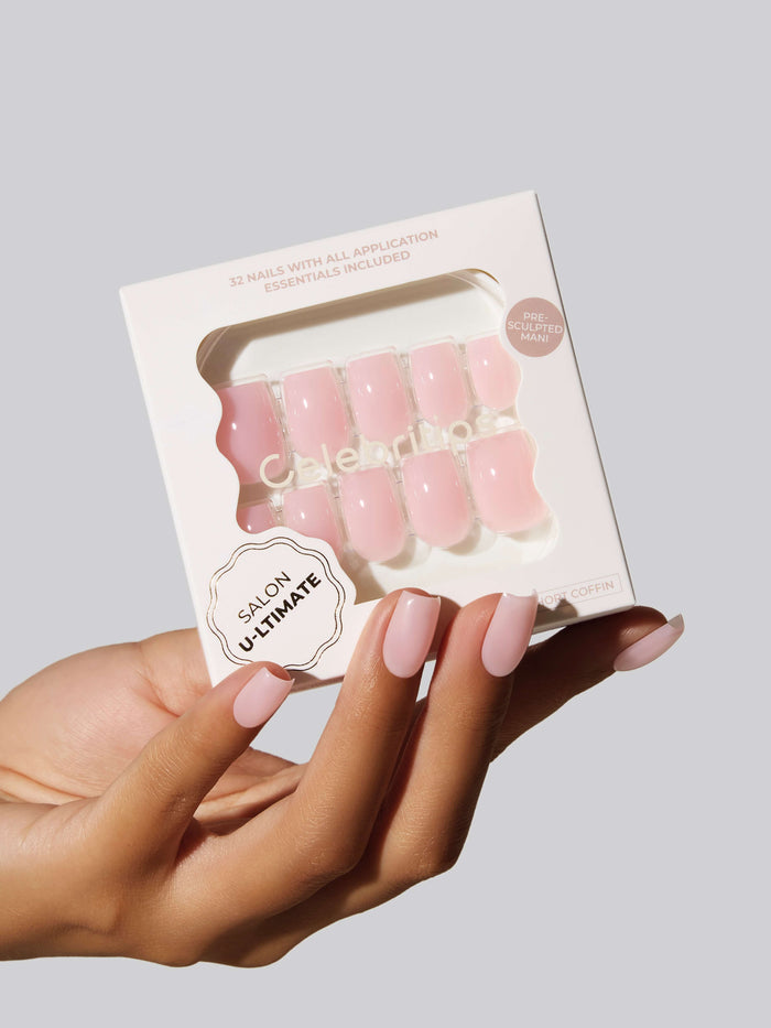 Hand with pink coffin press-on nails holding a box with the same nails.