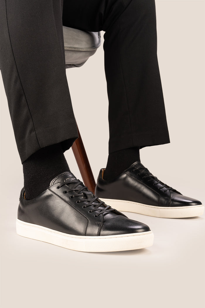 Black leather sneaker on a beige background
