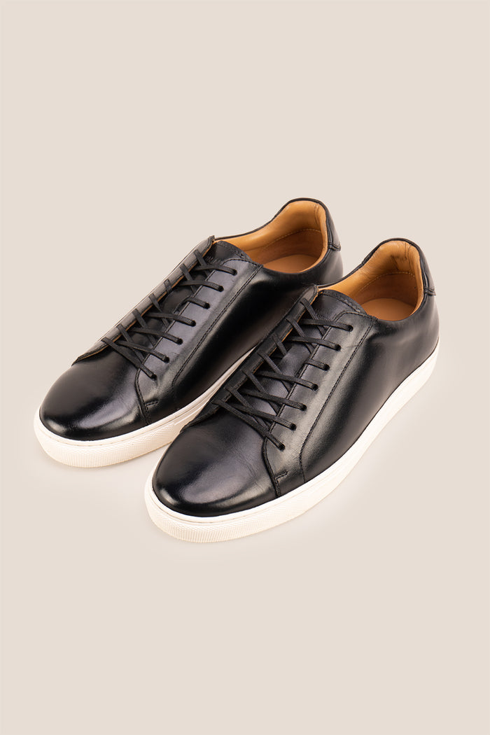 Black leather sneaker on a beige background