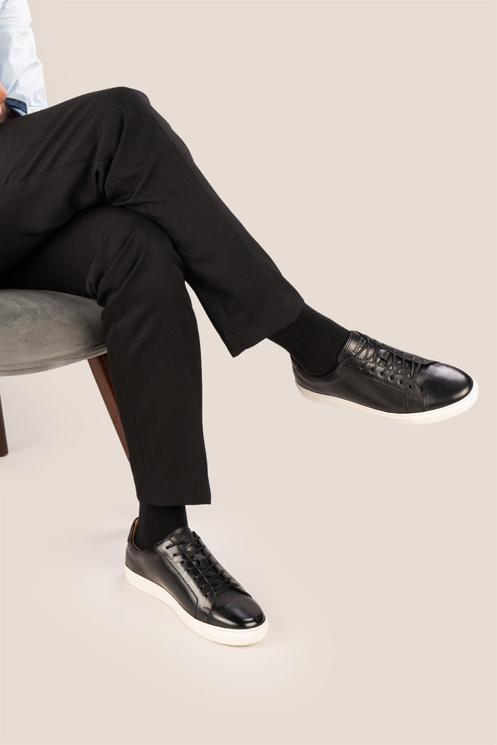 Black leather sneaker on a beige background