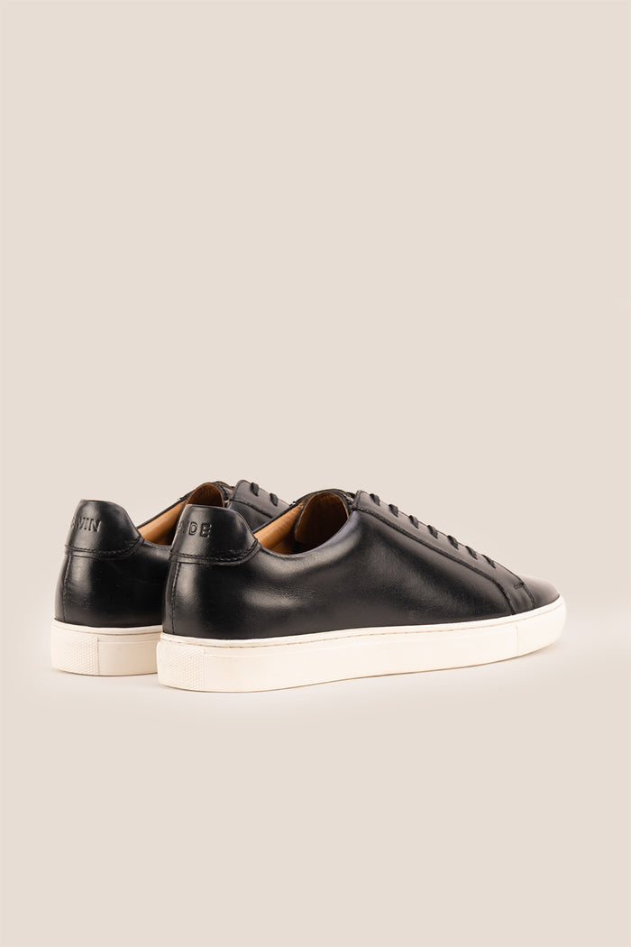 Black leather sneaker on a beige background