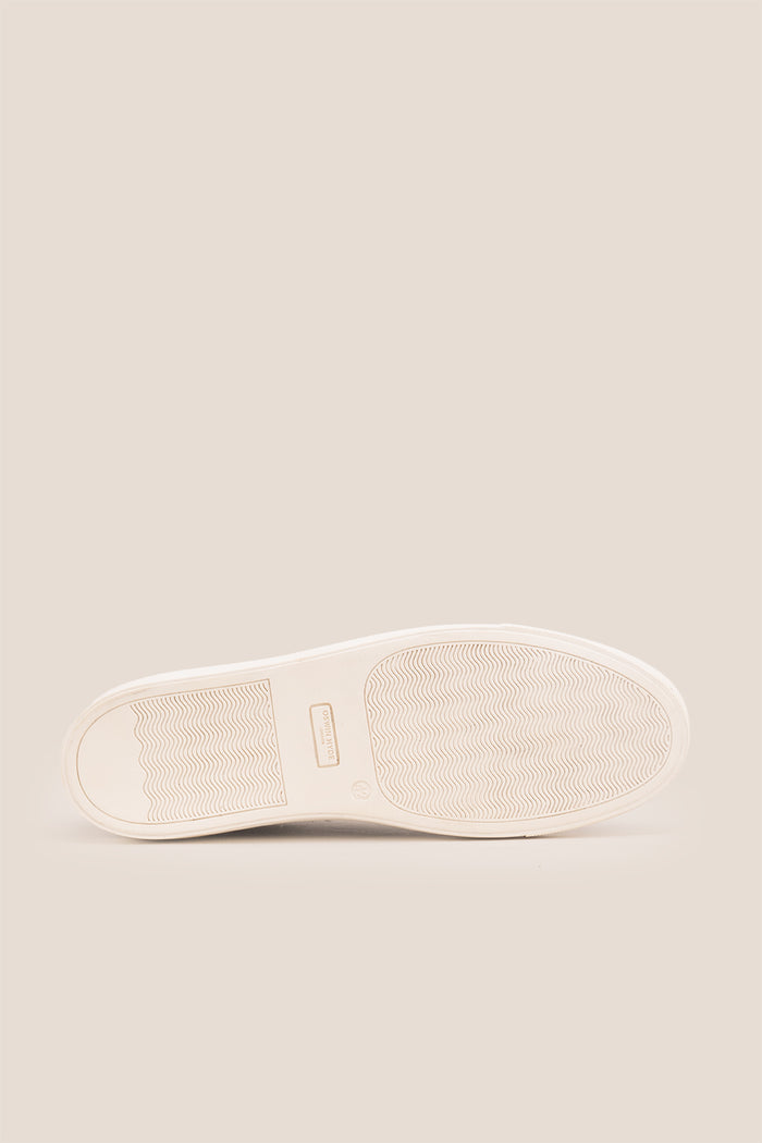 Black leather sneaker on a beige background