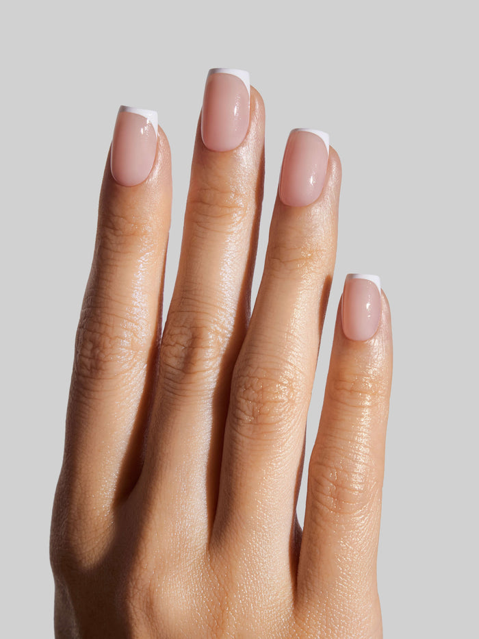 Hand with French Tip press-on nails on a plain background