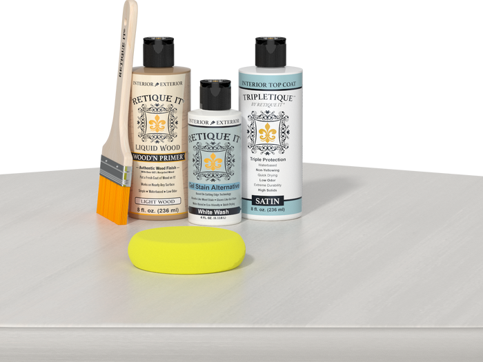 Retique It® Light Wood Wood’n Primer with White Wash Gel Stain Alternative, satin topcoat, brush, and yellow sponge on a white tabletop.