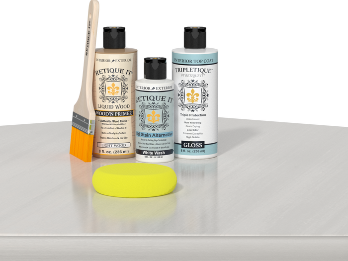 Retique It® Light Wood Wood’n Primer with White Wash Gel Stain Alternative, gloss topcoat, brush, and yellow sponge on a white tabletop.