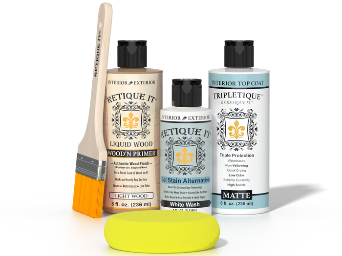 Retique It® Light Wood Wood’n Primer with White Wash Gel Stain Alternative, matte topcoat, brush, and yellow sponge on a reflective tabletop.