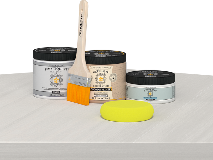 Retique It® White Wash Multipurpose Kit contents with Liquid Wood primer, White Wash gel stain alternative, PolyTique It® matte exterior top coat, paintbrush, and yellow sponge displayed on a white wood surface.