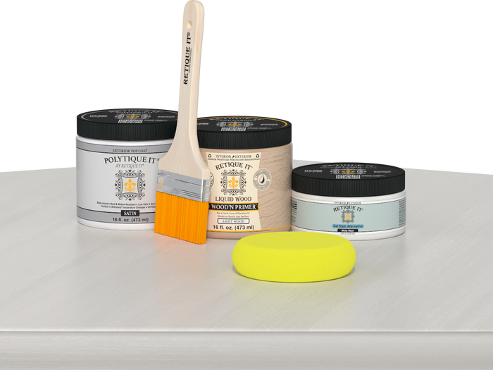 Retique It® White Wash Multipurpose Kit contents with Liquid Wood primer, White Wash gel stain alternative, PolyTique It® satin exterior top coat, paintbrush, and yellow sponge displayed on a white wood surface.