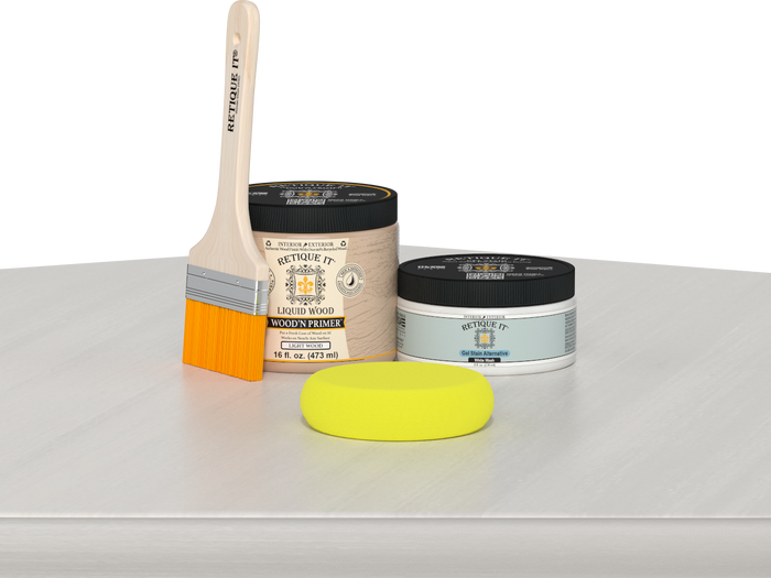 Retique It® White Wash Multipurpose Kit contents with Liquid Wood primer, White Wash gel stain alternative, paintbrush, and yellow sponge displayed on a white wood surface.