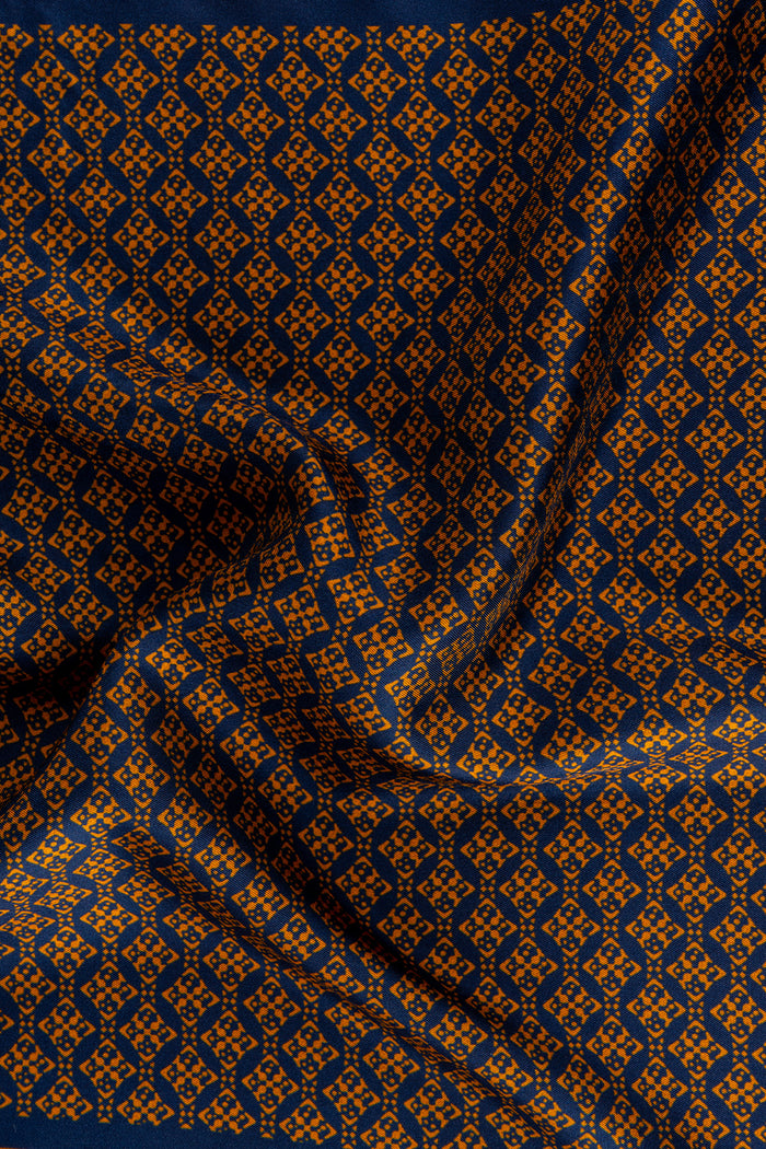 Men’s orange silk handkerchief with an intricate geometric pattern, crafted for weddings, formal occasions, or stylish smart dressing.