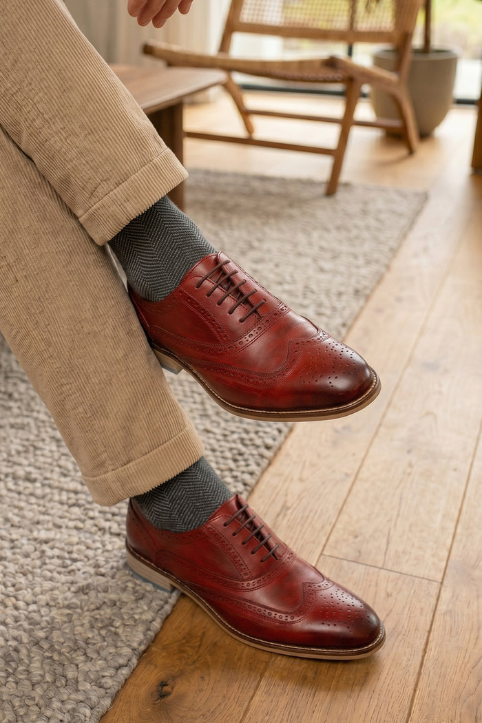 Man waringWinston cherry leather Oxford brogues for men featuring wingtip perforations and polished finish, ideal for formal and smart-casual occasions.